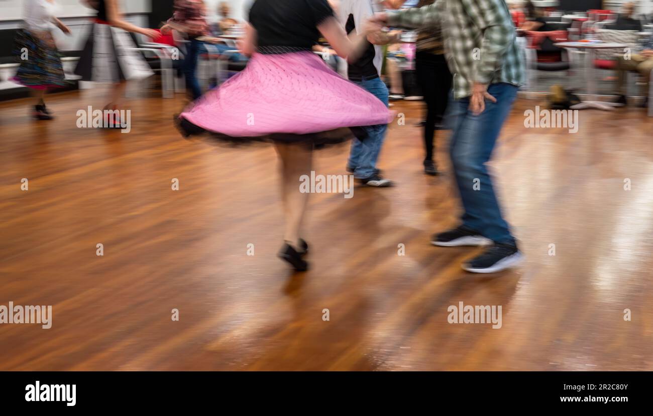 Leute, die gerne in einem Tanzclub tanzen. Bewegungsunschärfe eines pinkfarbenen fliegenden Rocks, der mit einer langsamen Verschlusszeit in der Kamera aufgenommen wurde. Stockfoto