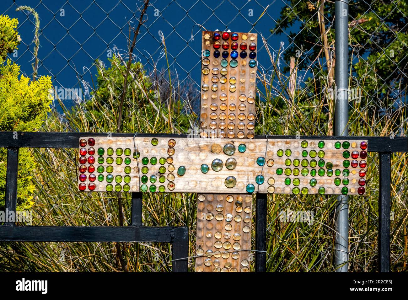 Bunte Glasperlen auf einem Holzkreuz auf einem Friedhof in Arizona nach einem Regensturm während der Monsunzeit Stockfoto