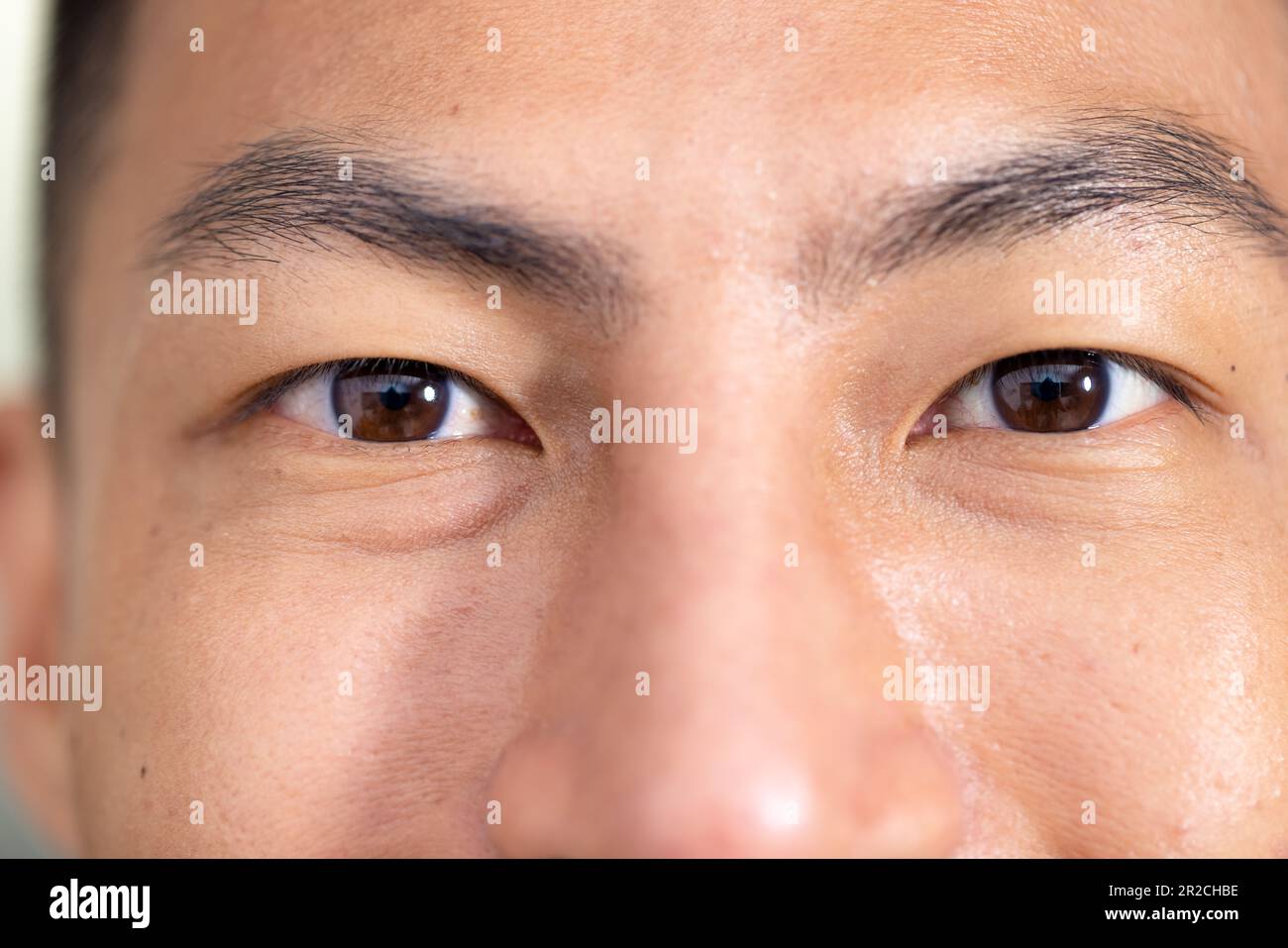 Nahaufnahme Porträt der Augen des unveränderten glücklichen asiatischen männlichen Arztes, der im Krankenhaus vor der Kamera lächelt Stockfoto