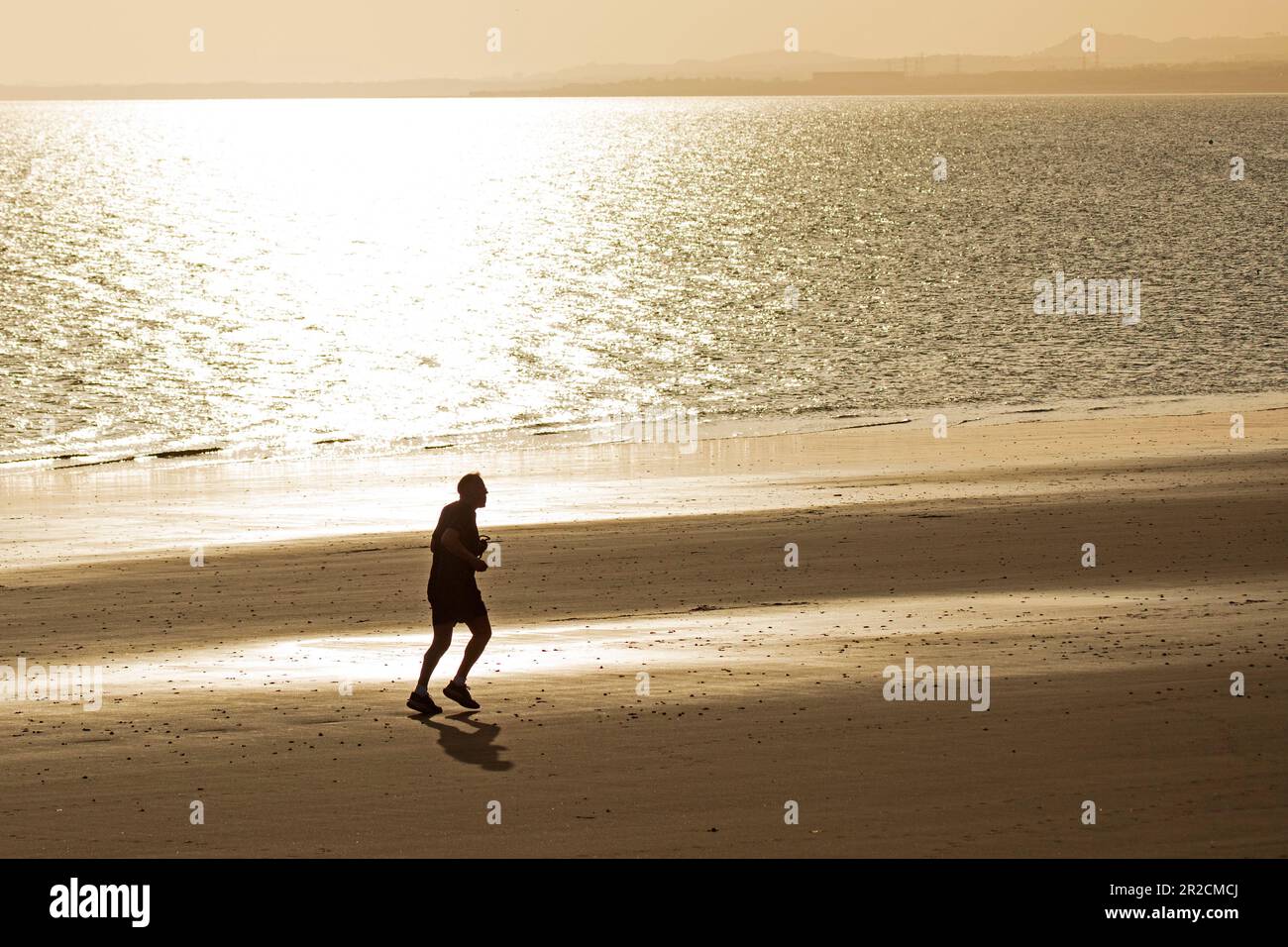 Portobello, Edinburgh, Schottland, Großbritannien. 19. Mai 2023 Ein einsamer Mann joggt am Ufer des Firth of Forth mit einer Temperatur von 11 Grad Celsius. Kredit: Arch White/alamy Live News. Stockfoto