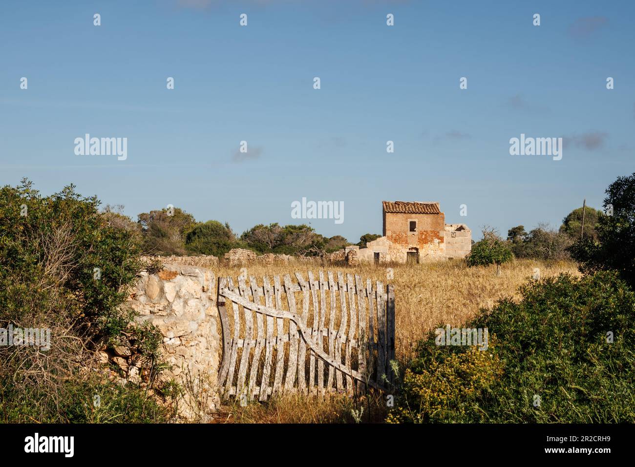 Verlassenes Bauernhaus auf den Feldern mit altem Holztor und Steinmauer auf Mallorca. Stockfoto