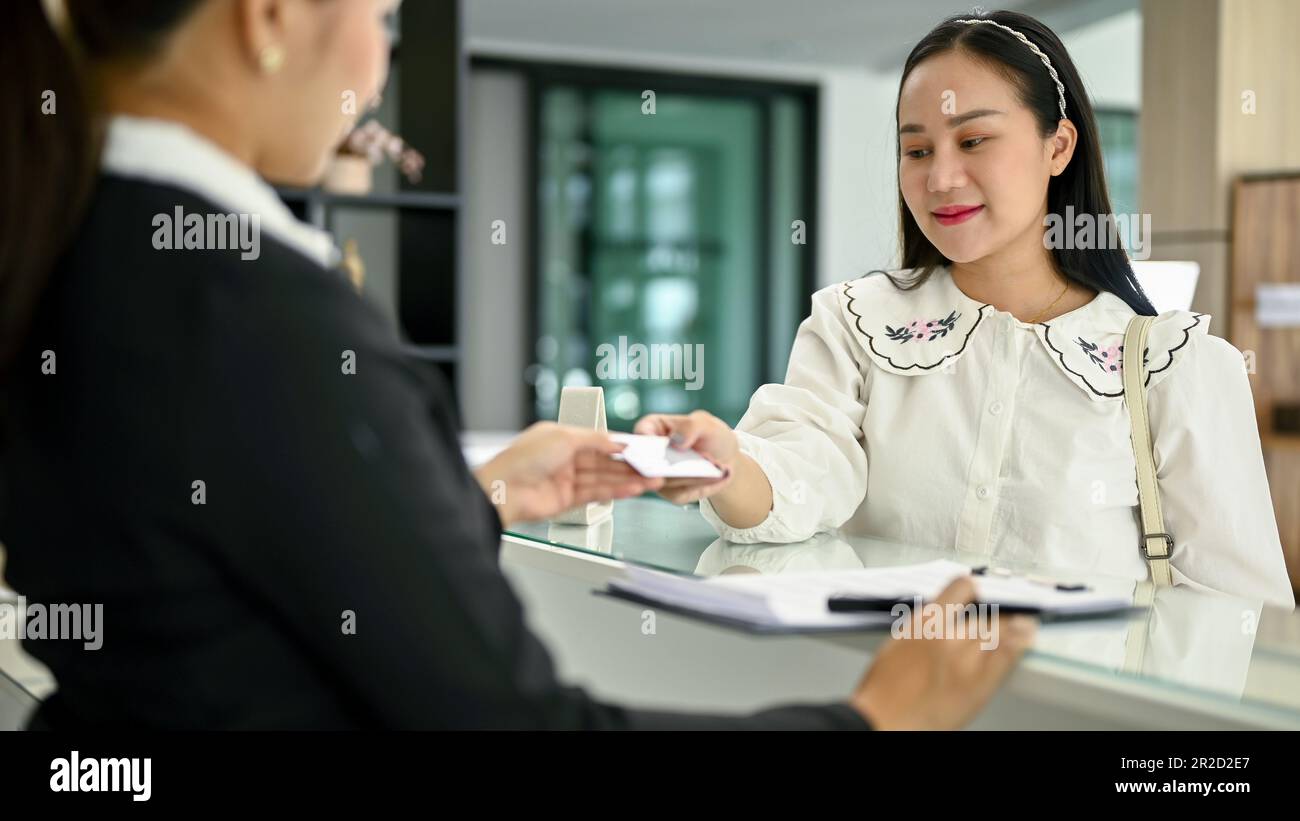 Eine asiatische Kundin bezahlt ihre Unterkunft mit ihrer Kreditkarte in der Lobby. Hospitality Service Konzept Stockfoto