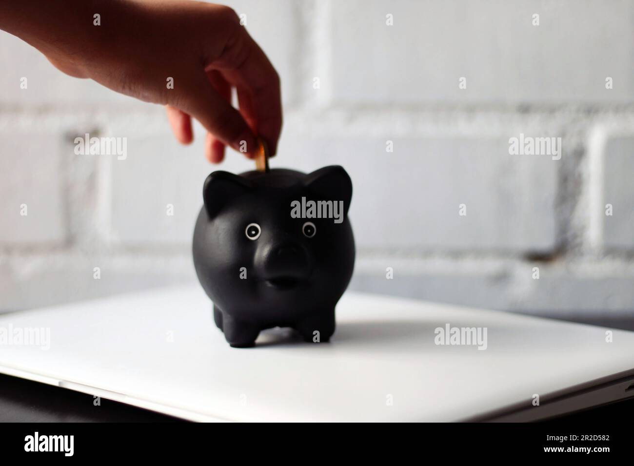Eine Person, die Geld in ein Sparschwein wirft. Stockfoto
