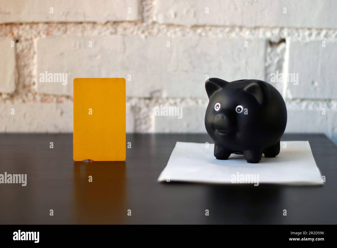 Sparschwein neben einer gelben Kreditkarte. Stockfoto