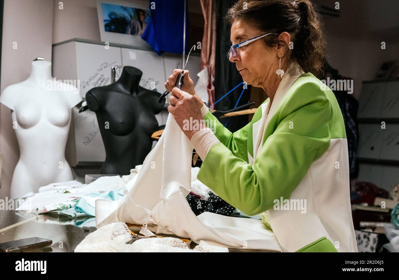 Schneiderin, die in ihrer Werkstatt ein Kleid auf den Kleiderbügel legt Stockfoto