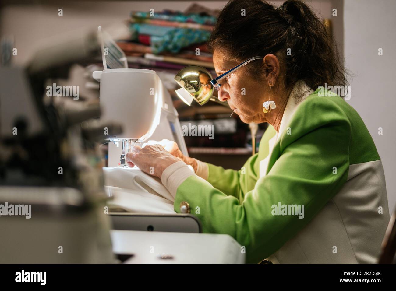 Die Schneiderin näht mit der Maschine in ihrer Nähwerkstatt Stockfoto
