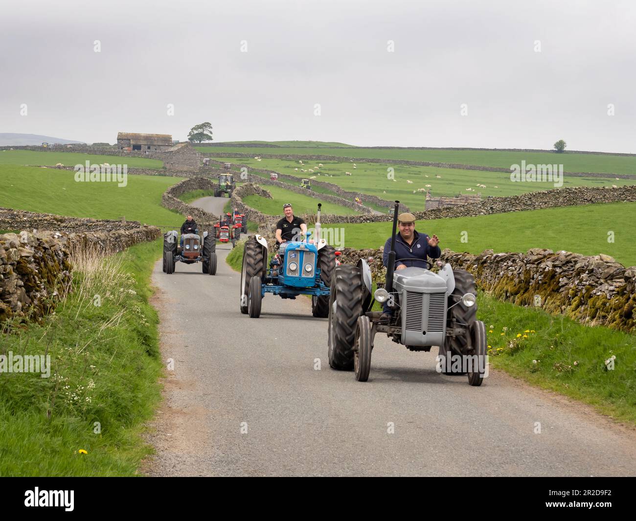 Ein Traktor fährt auf einer Straße über Settle, Yorkshire Dales, Großbritannien. Stockfoto