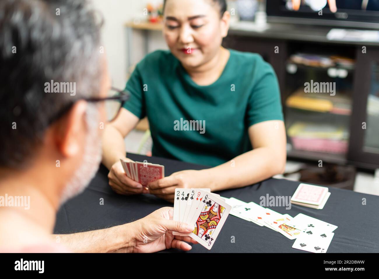 Paare, die zu Hause Karten spielen, für einen Date-Abend drinnen. Beide hielten Karten in der Hand und lächelten glücklich. Das Konzept für ein Spiel on, love, enjoy, h Stockfoto