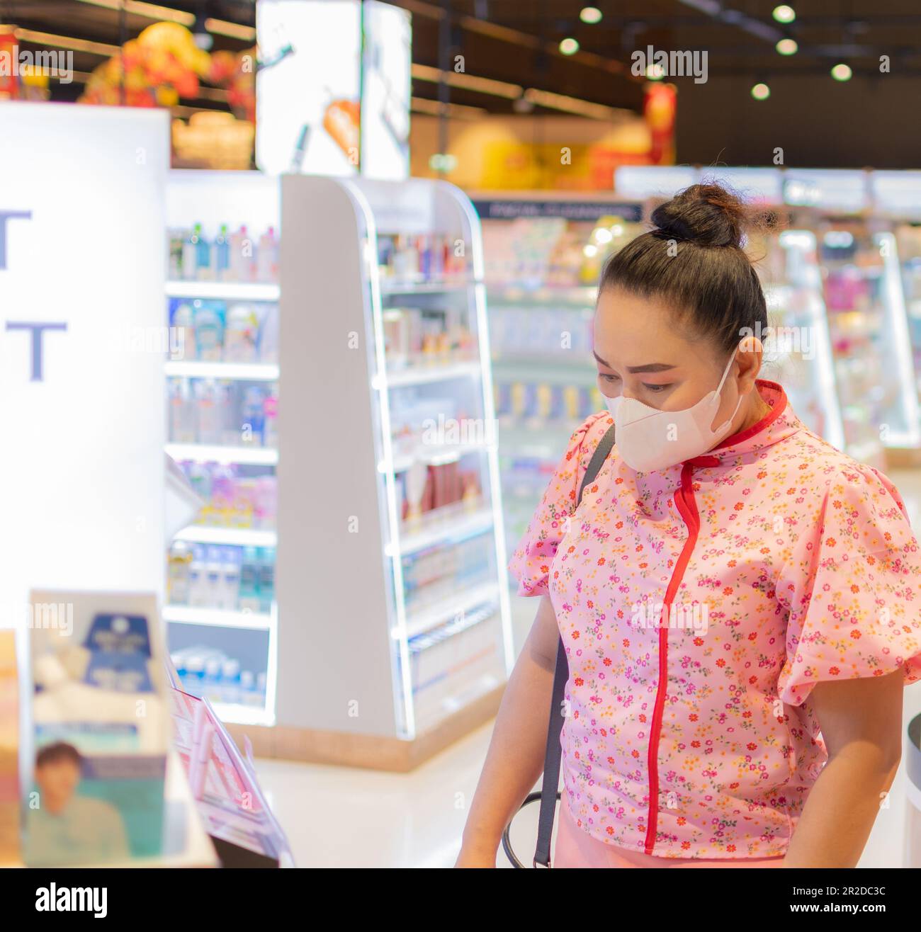 Eine maskierte Frau, die an ihrem besonderen Tag im Einkaufszentrum stand. Im Supermarkt Kosmetik, eine Abteilung an einem ungezwungenen Tag. Konzept Lifestyle, Shopping, Geschäfte Stockfoto