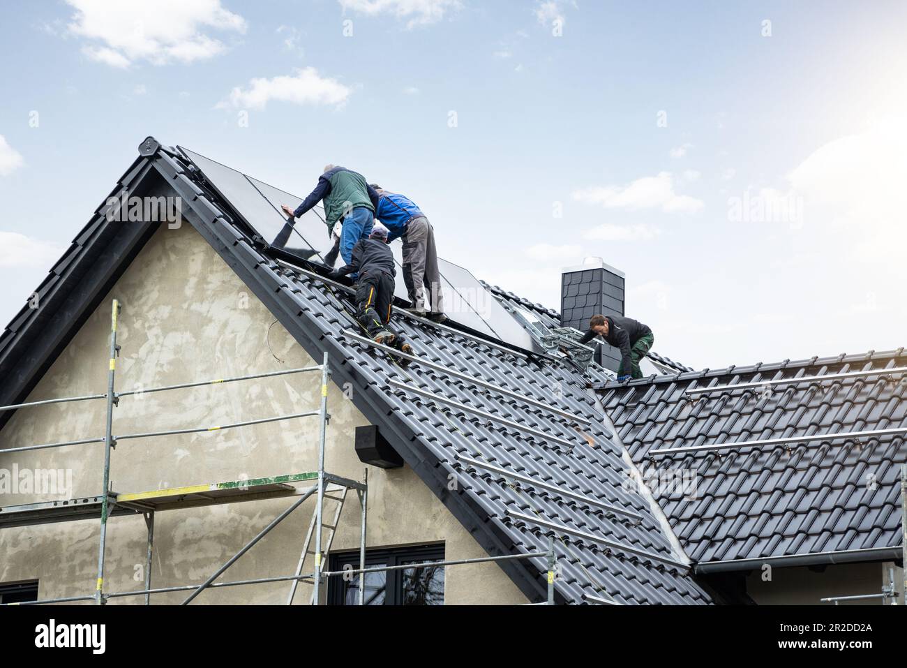Arbeiter, die Solarpaneele auf dem Dach eines deutschen Einfamilienhauses installieren Stockfoto