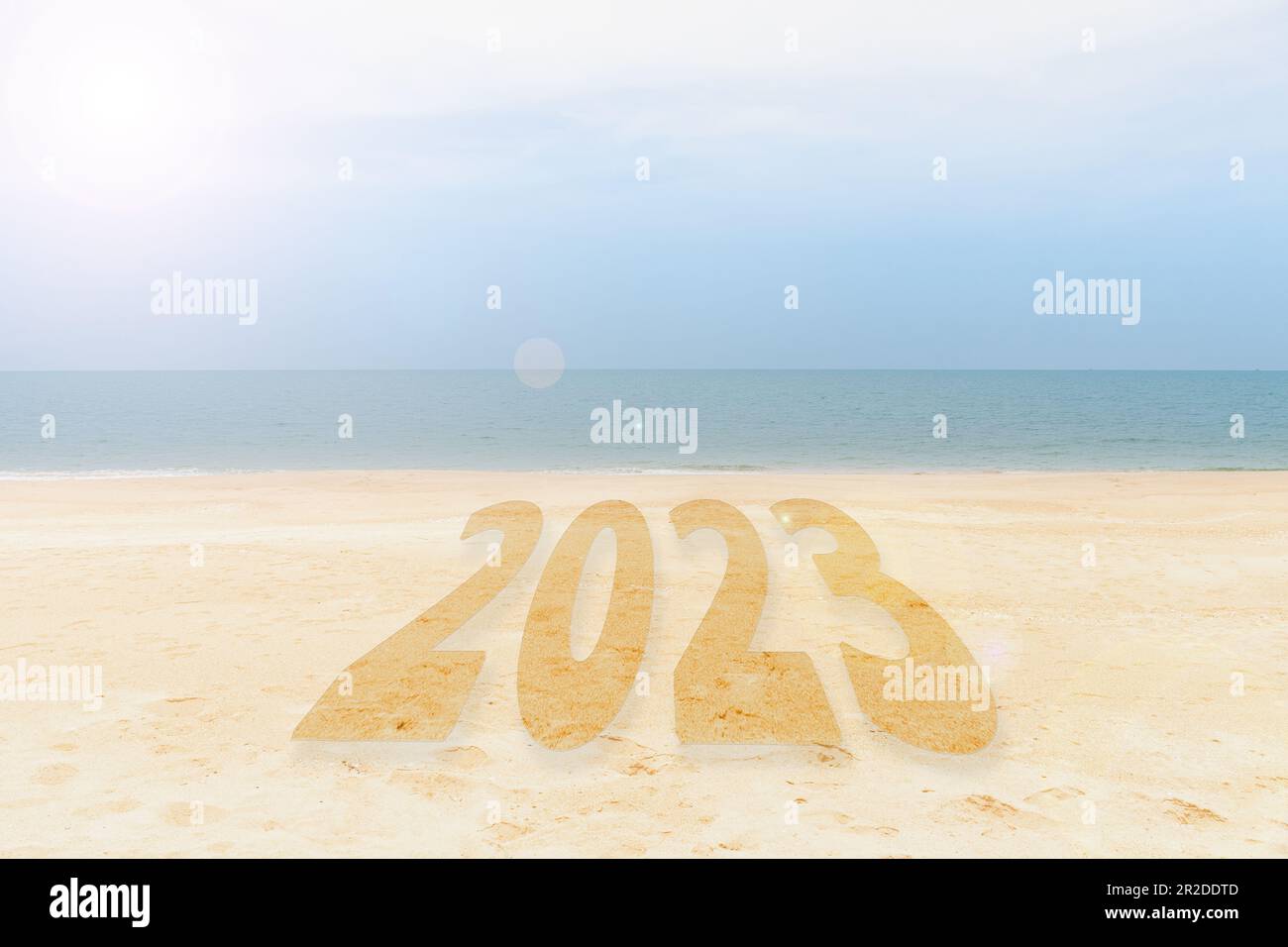 Neujahrskonzept 2023. Die Inschrift ist eine 2023-Nummer am Sandstrand. Sandstrand und Meereswelle wunderschöner Hintergrund. Schreiben Sie Briefe mit der Hand am Strand. Stockfoto