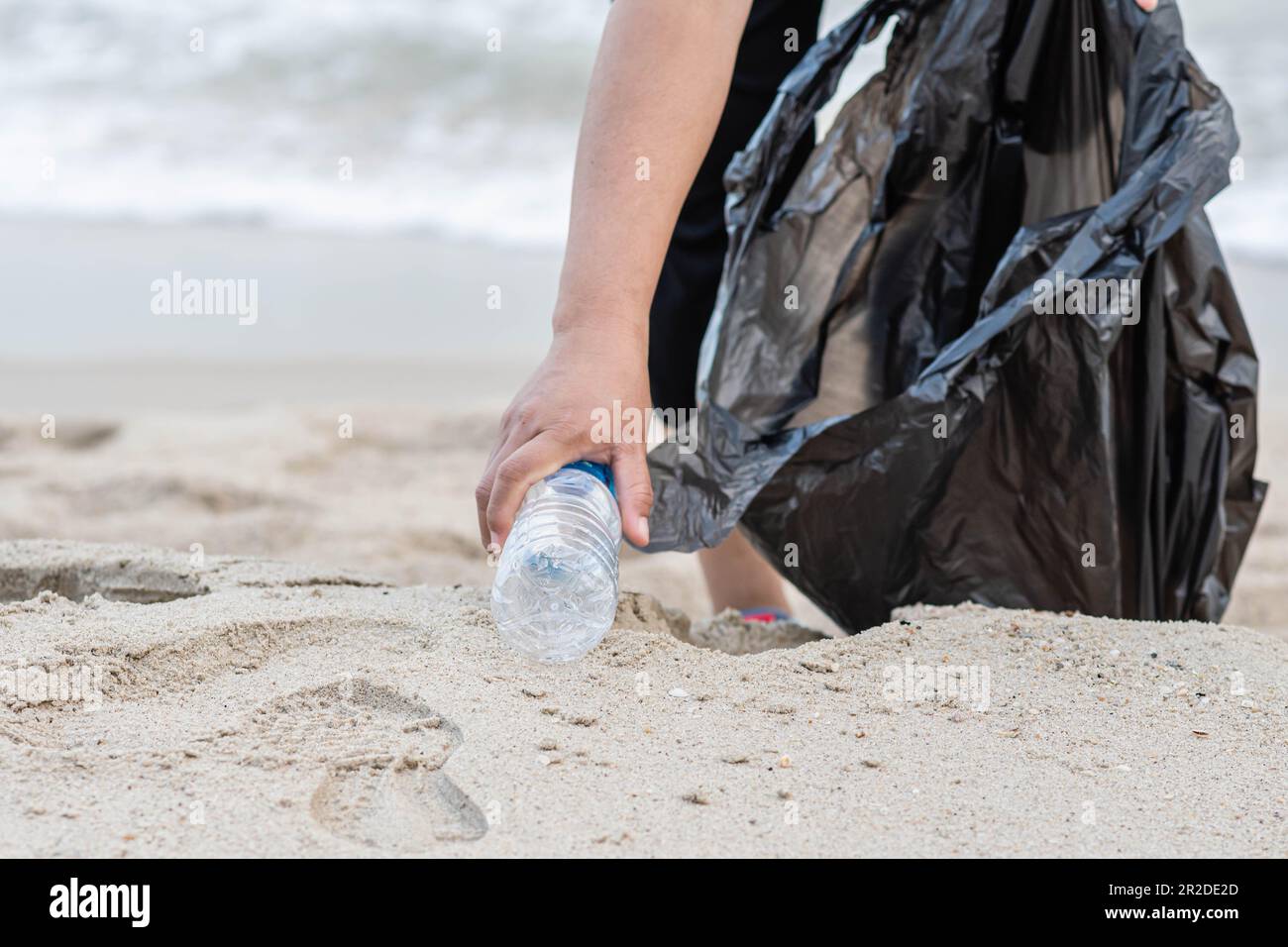 Eine Frau putzt, indem sie Plastikflaschen am Strand abholt. Konzept des Umweltschutzes, der Rettung der Welt, des Recyclings, der Reduzierung des globalen Warminhalts Stockfoto