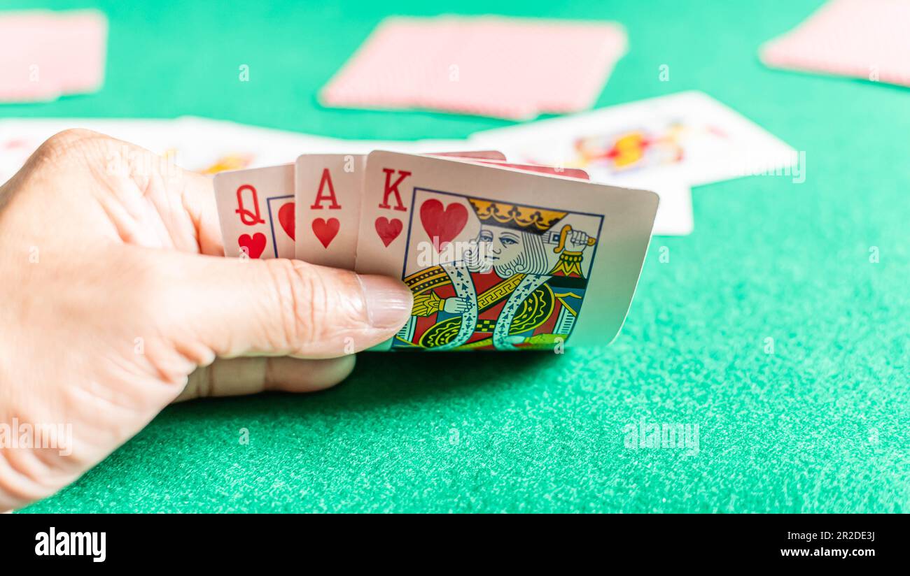 Songkhla, Hatyai, Thailand 12. März 2022: Nahaufnahme, selektiver Fokus, Die Hand eines Mannes, der im Rummy-Spiel Karten hält, wird auch als Kartenspiel bezeichnet. Unscharfer Hintergrund Stockfoto