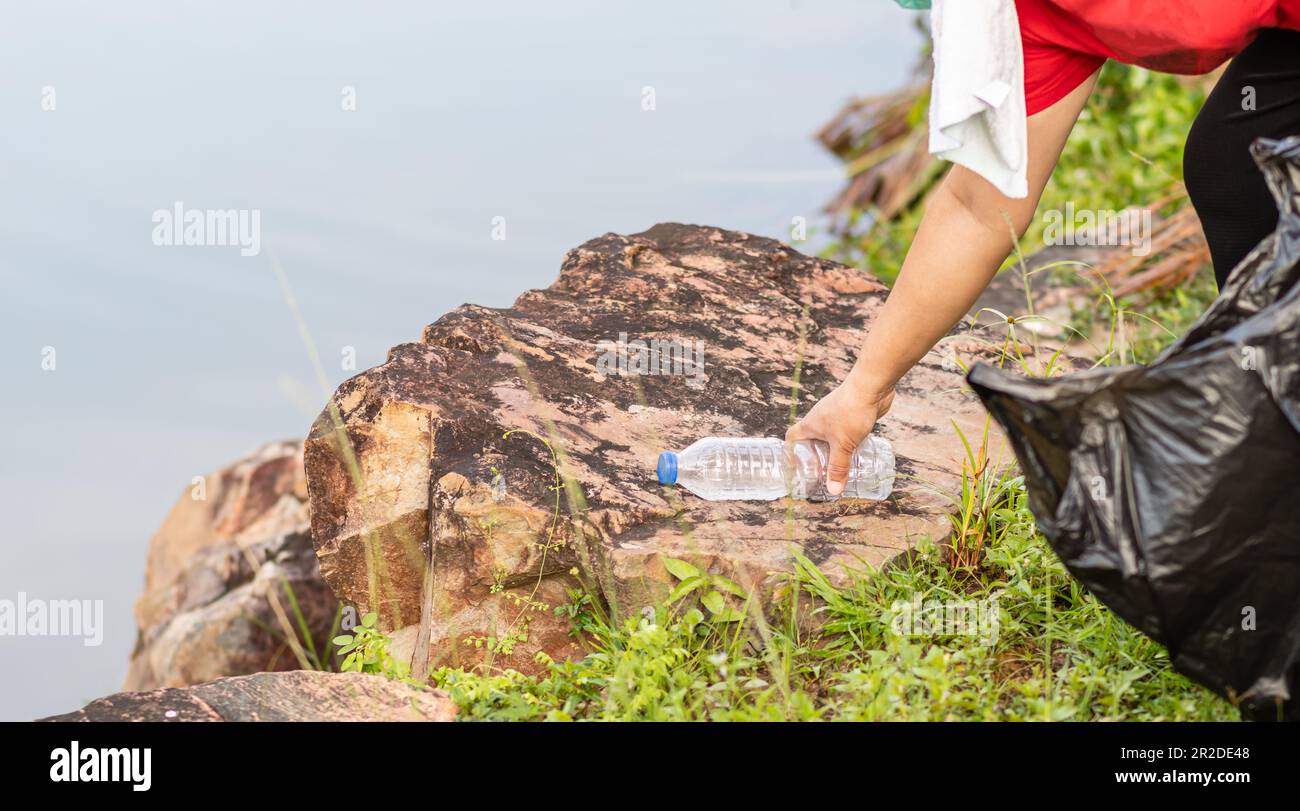 Eine Frau putzt, indem sie Plastikflaschen an einem natürlichen Wasserreservoir aufnimmt. Konzept des Umweltschutzes, der Rettung der Welt, des Recyclings, des redu Stockfoto