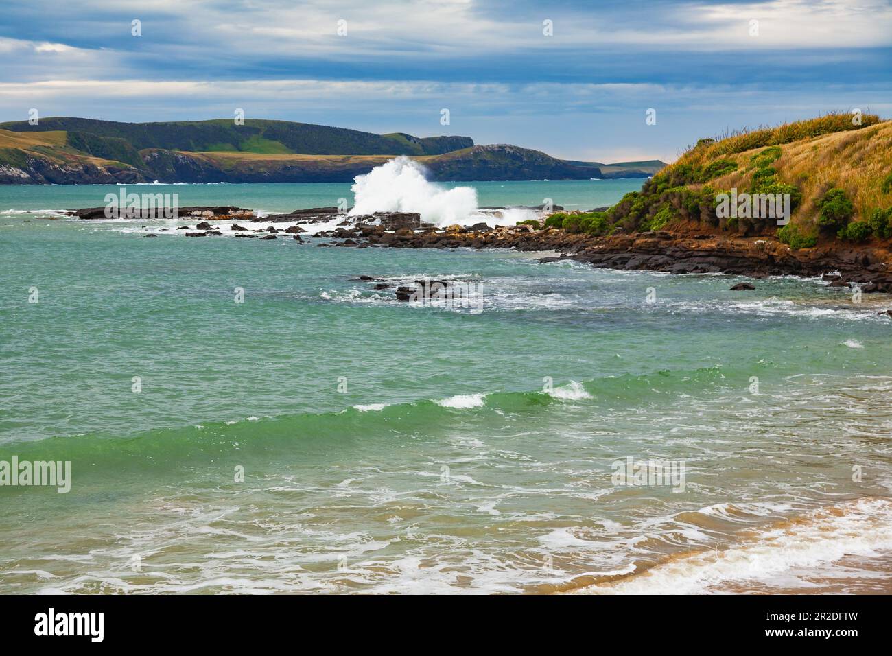 Wellen stürzen auf den Felsen der Porpoise Bay im Southland District von South Island, Neuseeland Stockfoto