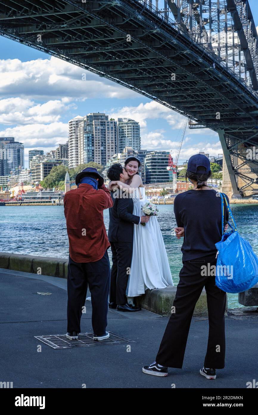 Ein asiatisches Paar, das Hochzeitsfotos unter der Sydney Harbour Bridge, Australien, gemacht hat Stockfoto