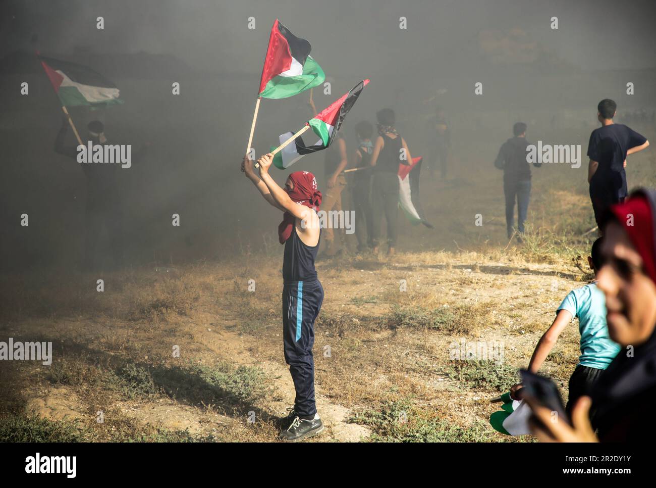 Gaza, Palästina. 18. Mai 2023. Ein Palästinenser schwenkt mit einer palästinensischen Flagge, wenn er gegen den israelischen "flaggenmarsch" im östlichen Gazastreifen in der Nähe der Grenze zu Israel marschiert. Die Palästinenser hielten ihren eigenen "flaggenmarsch", um gegen den rechten israelischen "flaggenmarsch" zu protestieren, der anlässlich des Quds Day in Jerusalem stattfand. Die Palästinenser betrachten die israelische Feier des Quds-Tages seit langem als Provokation. Kredit: SOPA Images Limited/Alamy Live News Stockfoto