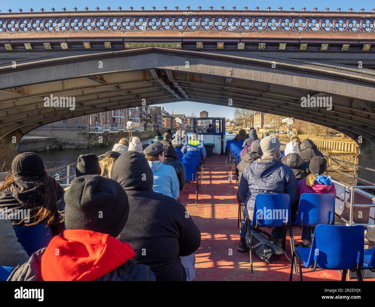 Touristen sitzen auf dem offenen Oberdeck eines Flusskreuzfahrtschiffs, das unter einer Skeldergate-Brücke in York vorbeifuhr. UK Stockfoto
