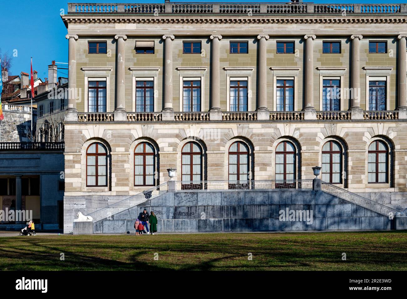 Fröhliche Familie an einem sonnigen Wintertag vor dem Eynard Palace im Bastions Park. Kinderwagen an der Seite. Stockfoto