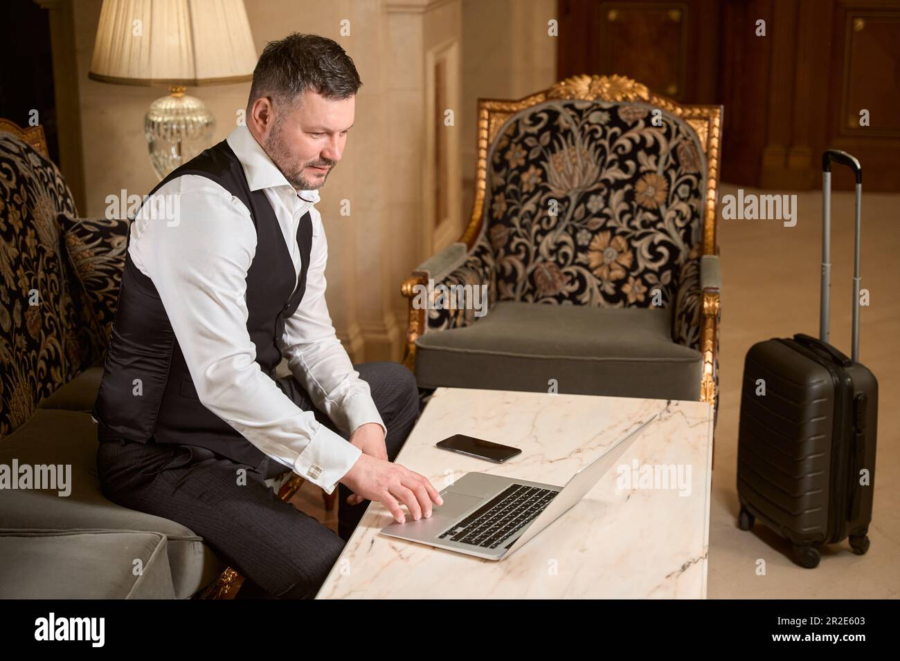 Geschäftsmann, der an einem Laptop am Tisch im Hotel arbeitet Stockfoto