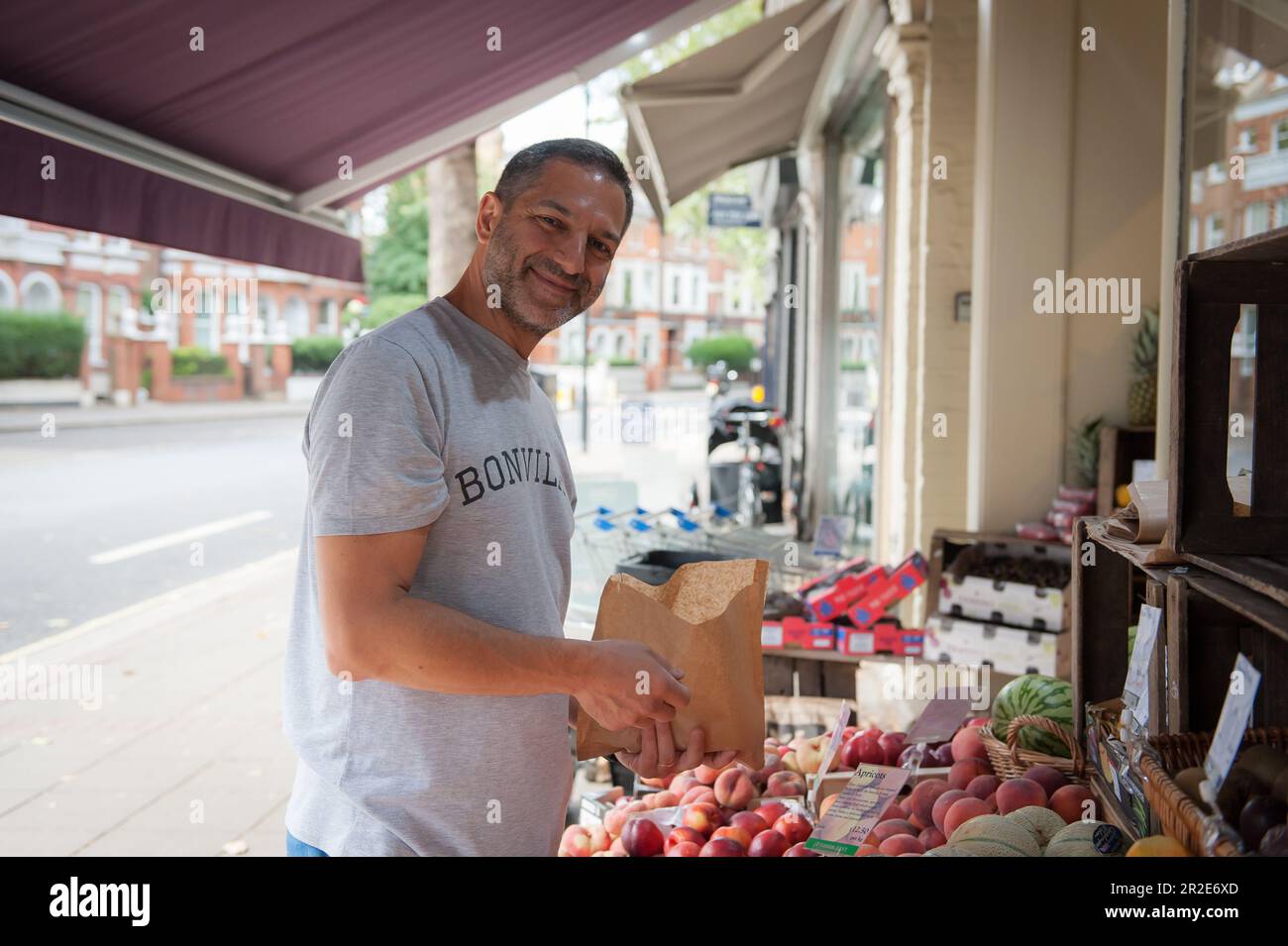 Bailey und Sage, ein unabhängiges Delikatessengeschäft in Parsons Green, einer Gegend in London. Ein Mann, der Obst auswählt. Stockfoto Bailey und Sage, ein unabhängiges Delikatessengeschäft in Parsons Green, einer Gegend in London. Ein Mann, der Obst auswählt. Stockfoto