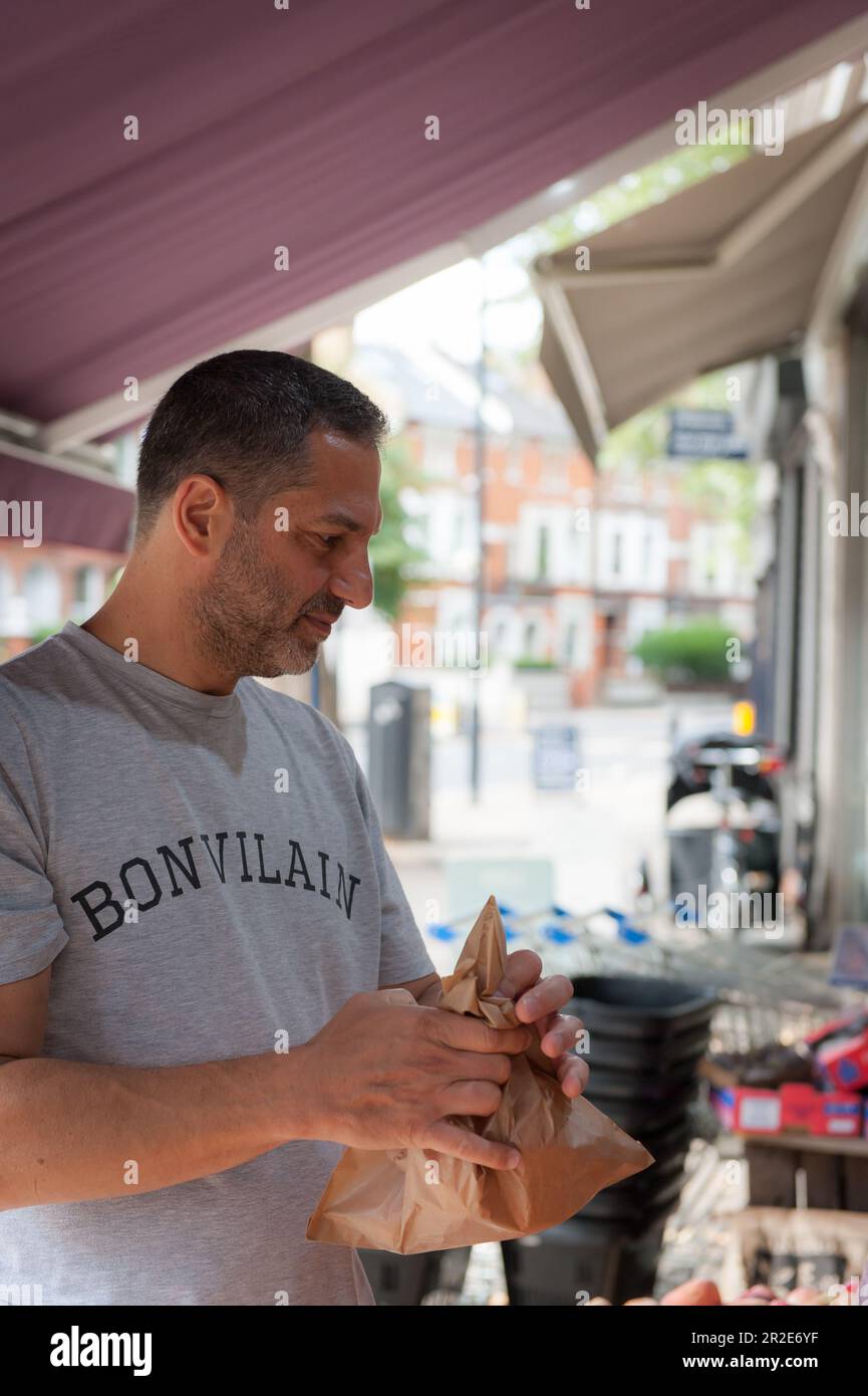 Bailey und Sage, ein unabhängiges Delikatessengeschäft in Parsons Green, einer Gegend in London. Ein Mann, der Obst auswählt. Stockfoto Bailey und Sage, ein unabhängiges Delikatessengeschäft in Parsons Green, einer Gegend in London. Ein Mann, der Obst auswählt. Stockfoto