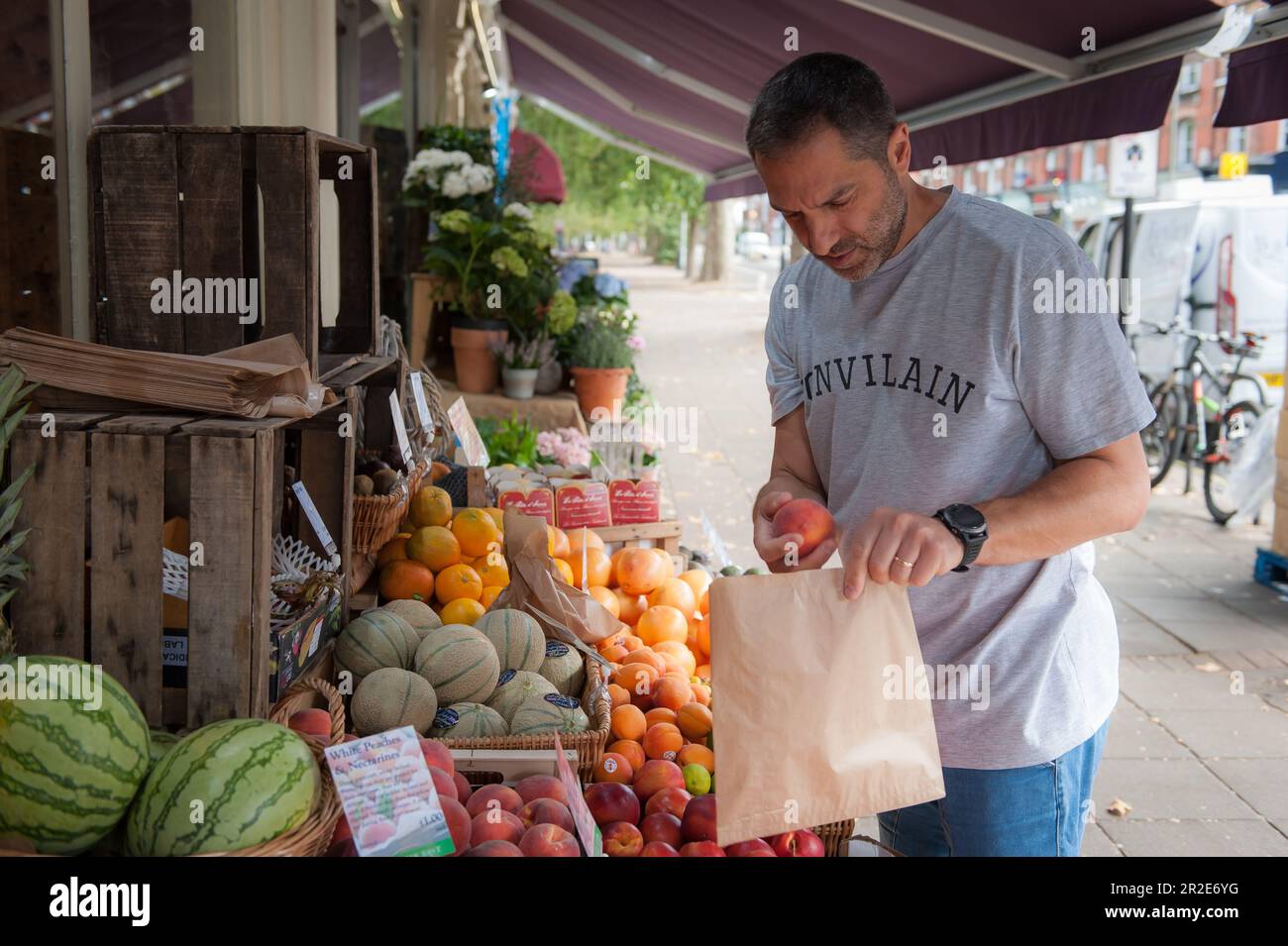 Bailey und Sage, ein unabhängiges Delikatessengeschäft in Parsons Green, einer Gegend in London. Ein Mann, der Obst auswählt. Stockfoto