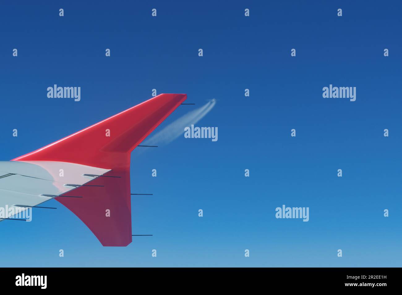 Ansicht eines Flugzeugflügels während des Fluges und eines ankommenden Flugzeugs in der Ferne. Luftfahrt, Aerodynamik und Flugverkehrskonzepte Stockfoto
