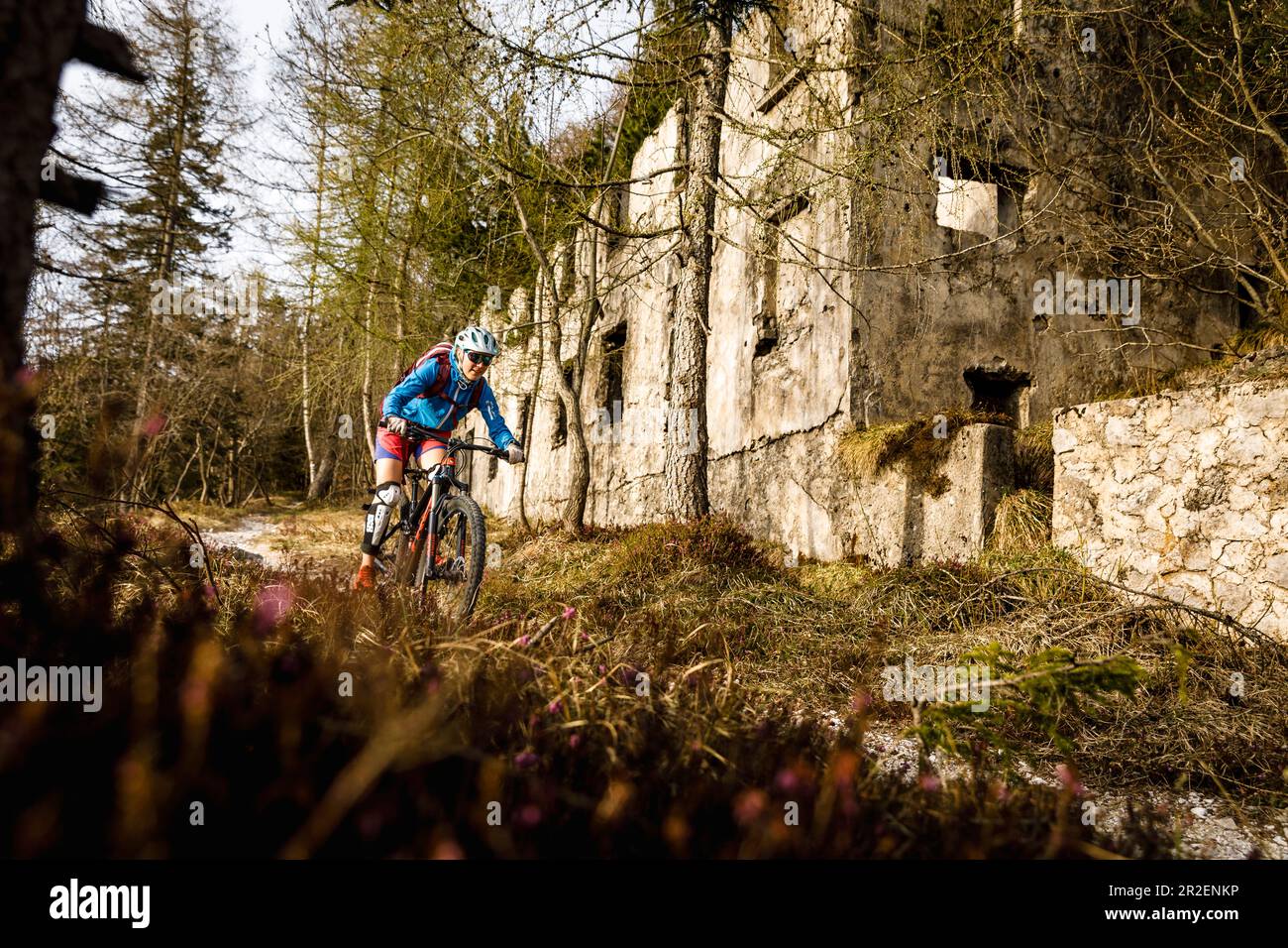 Junge Frau fährt mit dem Mountainbike an einer Ruine vorbei, Idro-See, Italien Stockfoto