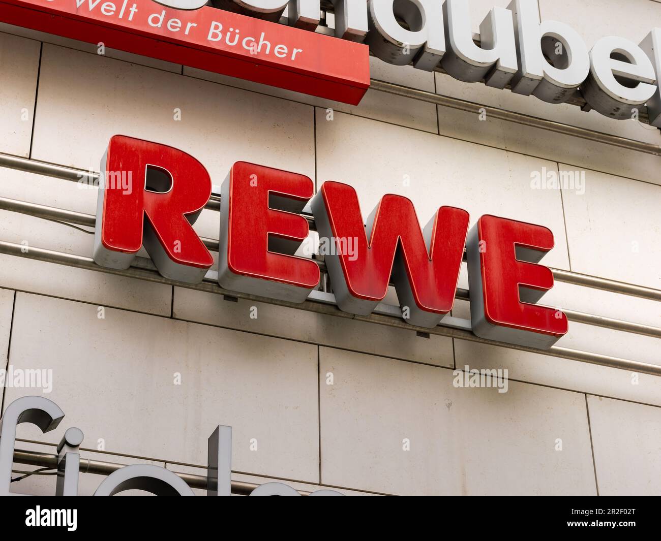 REWE-Logo des Supermarkts auf einer Gebäudefassade. Deutsches Lebensmittelgeschäft und Einzelhändler. Als Werbung an einer Außenseite unterschreiben. Stockfoto