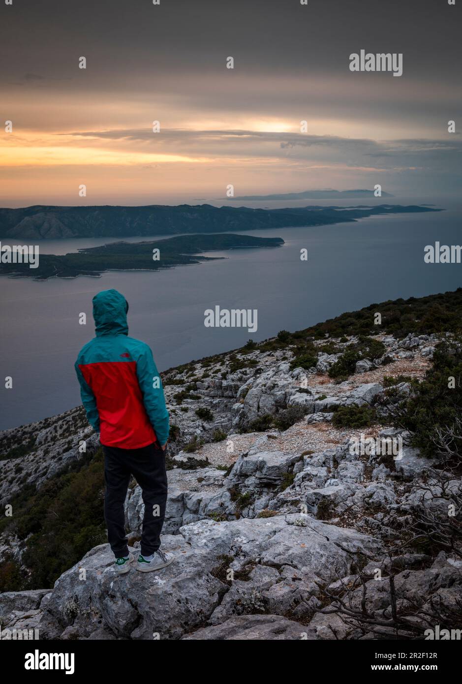 Mann, der die Insel Hvar vom Aussichtspunkt Vidova Gora auf Brac bei Sonnenuntergang, Kroatien, betrachtet Stockfoto