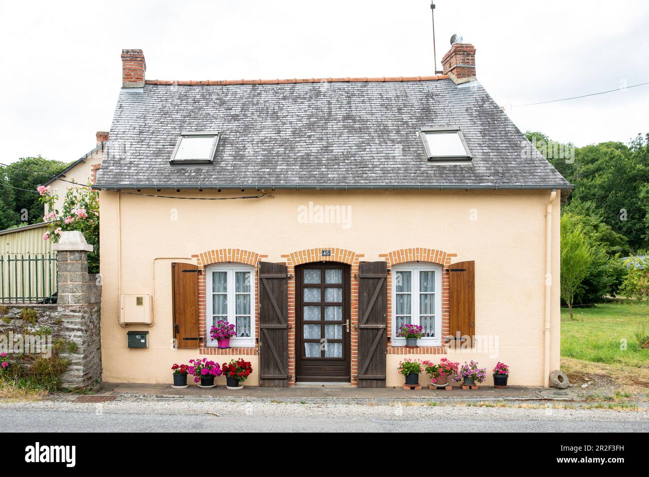 Kleines französisches Haus mit Holzläden und Blumentöpfen in Langon, Departement Ille-et-Vilaine, Bretagne, Frankreich, Europa Stockfoto