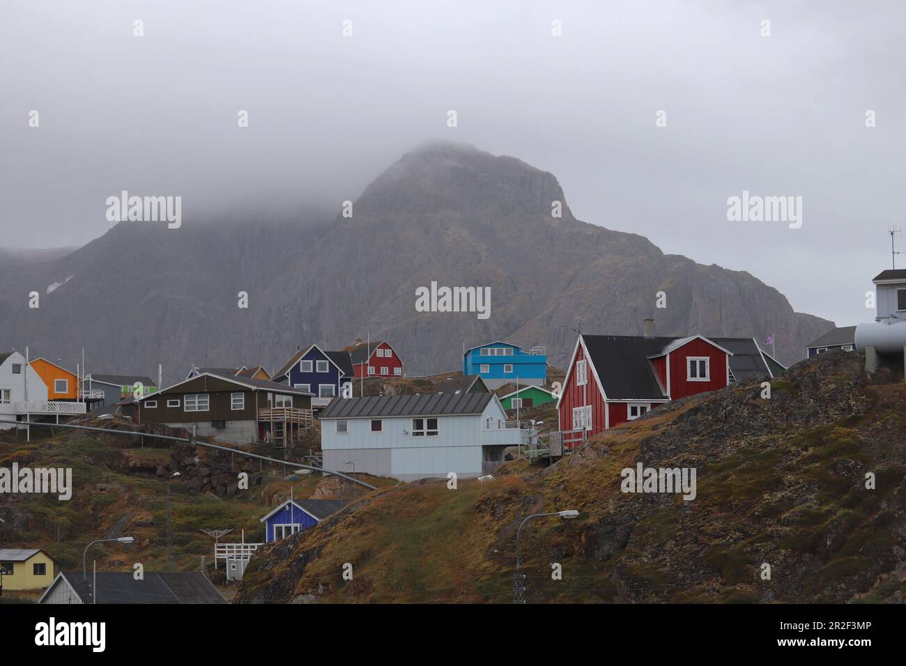 Sisimiut in Westgrönland; zweitgrößte Stadt Grönlands; Stadtbild; farbenfrohe Holzhäuser in felsigem, hügeligem Gelände; überirdische Wasserrohre supp Stockfoto
