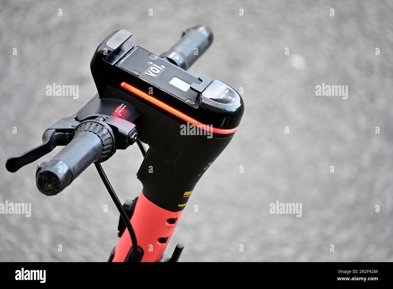 VOI E-Scooter Nahaufnahme der Griffstangen und des Handyhaltens und des Buchungshakens mit roter Anzeige, die anzeigt, dass eine Aufladung erforderlich ist Stockfoto