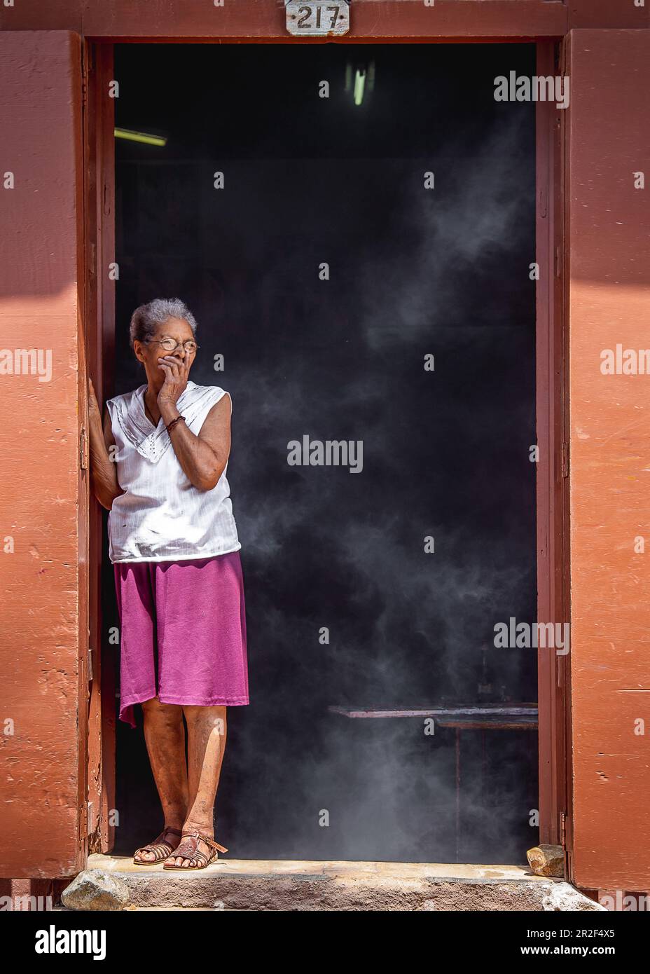 Frau hustet, weil sie in der Küche raucht, Trinidad, Kuba Stockfoto