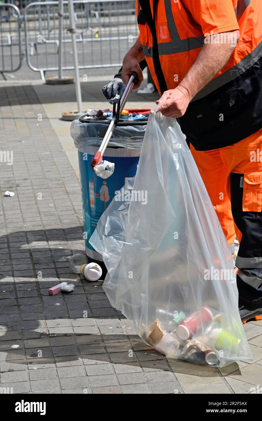 Gemeindemitarbeiter in Warnkleidung nimmt weggeworfene Abfälle von der Straße auf und verpackt sie nach einer öffentlichen Veranstaltung (Bristol Marathon) Stockfoto