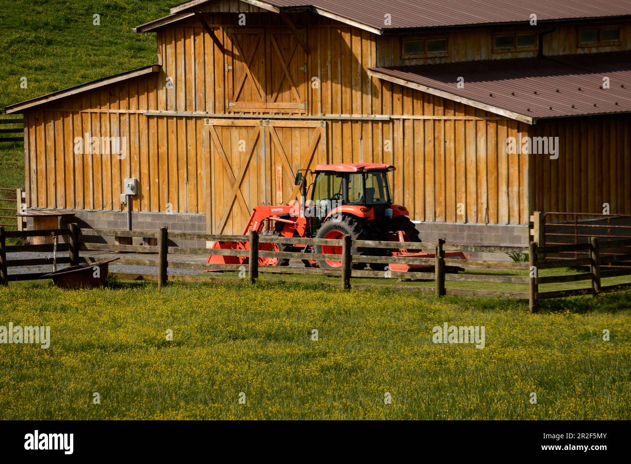Ein Kubota-Traktor, der neben einer Rinderscheune auf einem Bauernhof in Abingdon, Virginia, geparkt ist. Stockfoto
