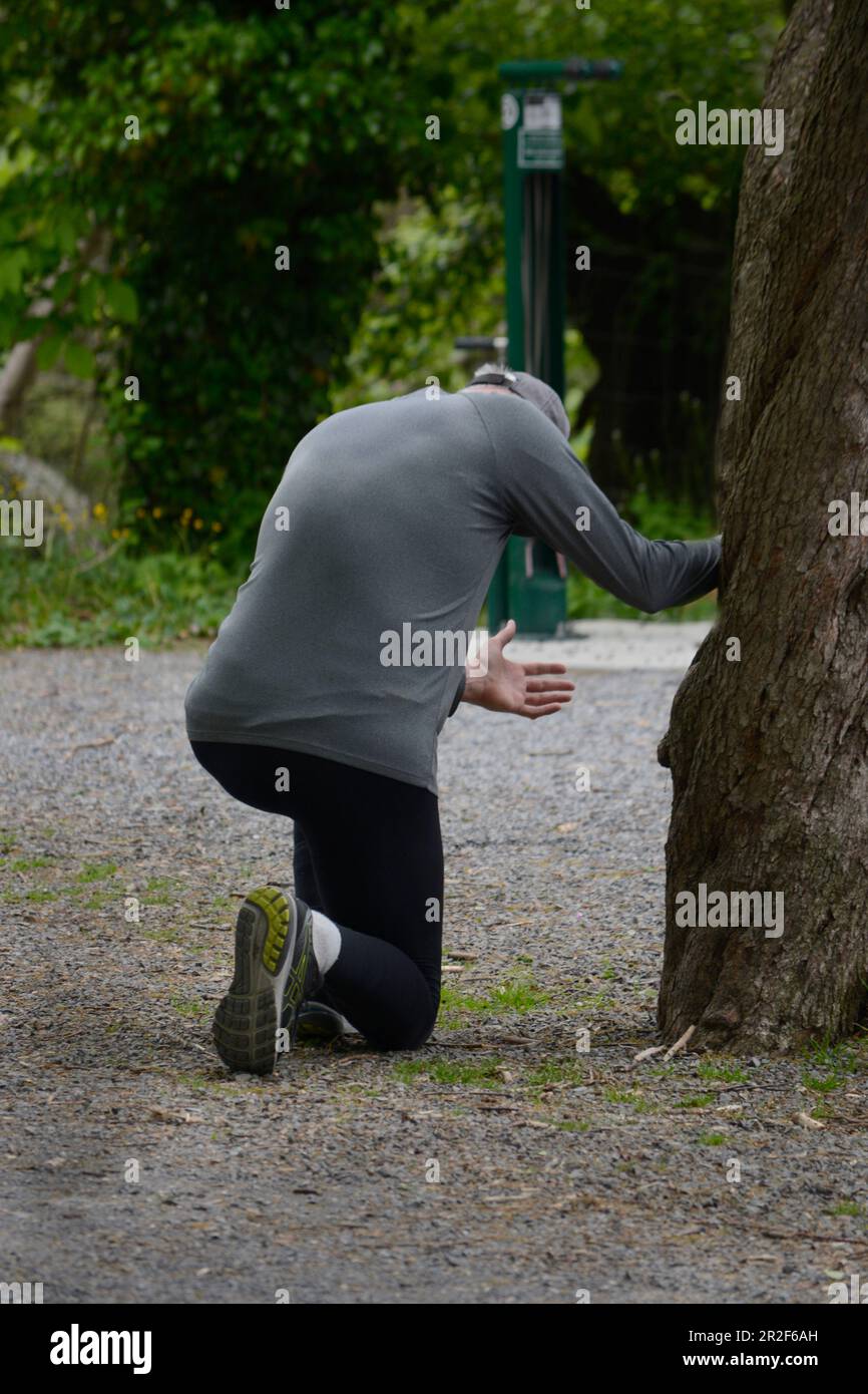 Ein Mann pausiert beim Joggen, um auf die Knie zu gehen und in Abingdon, Virginia, zu beten. Stockfoto