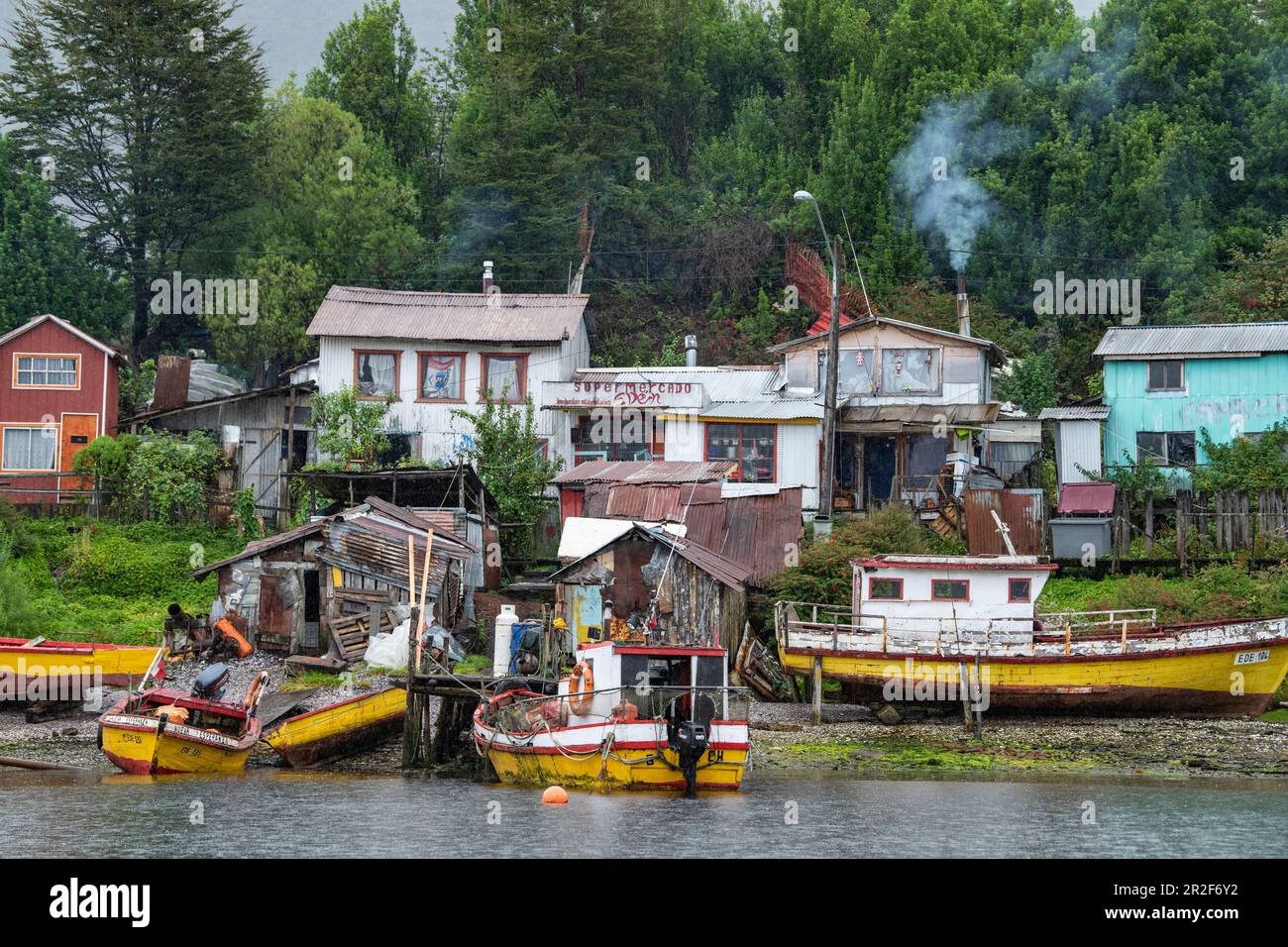 Boote und Hütten säumen dieses Segment der ansonsten dünn besiedelten Fjorde, Villa Puerto Edén, Wellington Island, Natales, Magallanes y de la Antarti Stockfoto