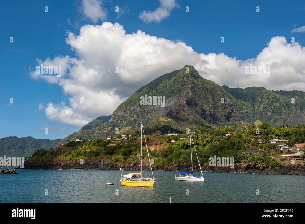Zwei Segelboote liegen in der Sonne vor einem riesigen Berg, Atuona, Hiva OA, Marquesas-Inseln, Französisch-Polynesien, Südpazifik Stockfoto