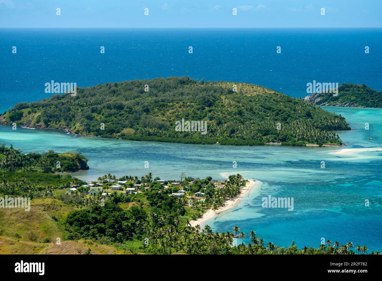 Blick auf eine kleine Siedlung, zwei Inseln und das Meer, Riffe in zahlreichen Blau- und Grüntönen, Mamanuca-Inseln, Fidschi, Südpazifik Stockfoto