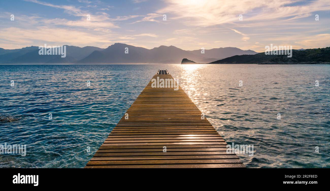 Sonnenaufgang am Steeg ins Wasser vor einem Bergpanorama, Agrigates Wüste, Korsika Stockfoto