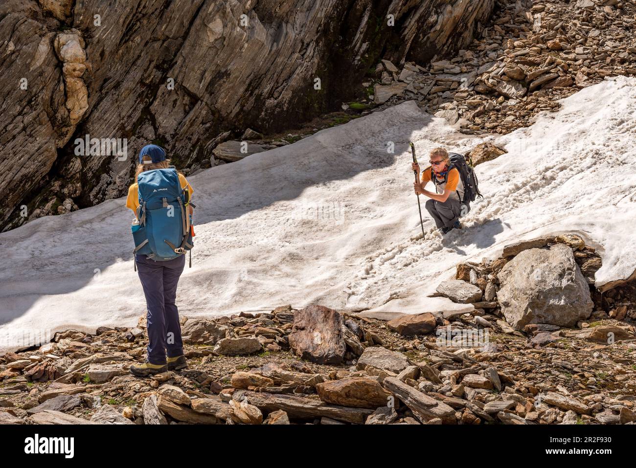 Wanderin rutscht geschickt über den alten Schnee, Trekking del Laghetti Alpini, Tessin, Schweiz Stockfoto