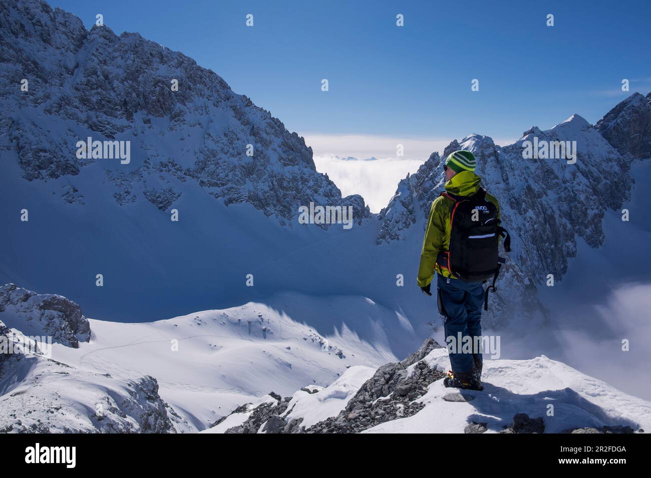 Mann mit Rucksack auf dem Gipfel in Tajakopf in Ehrwald im Winter Stockfoto
