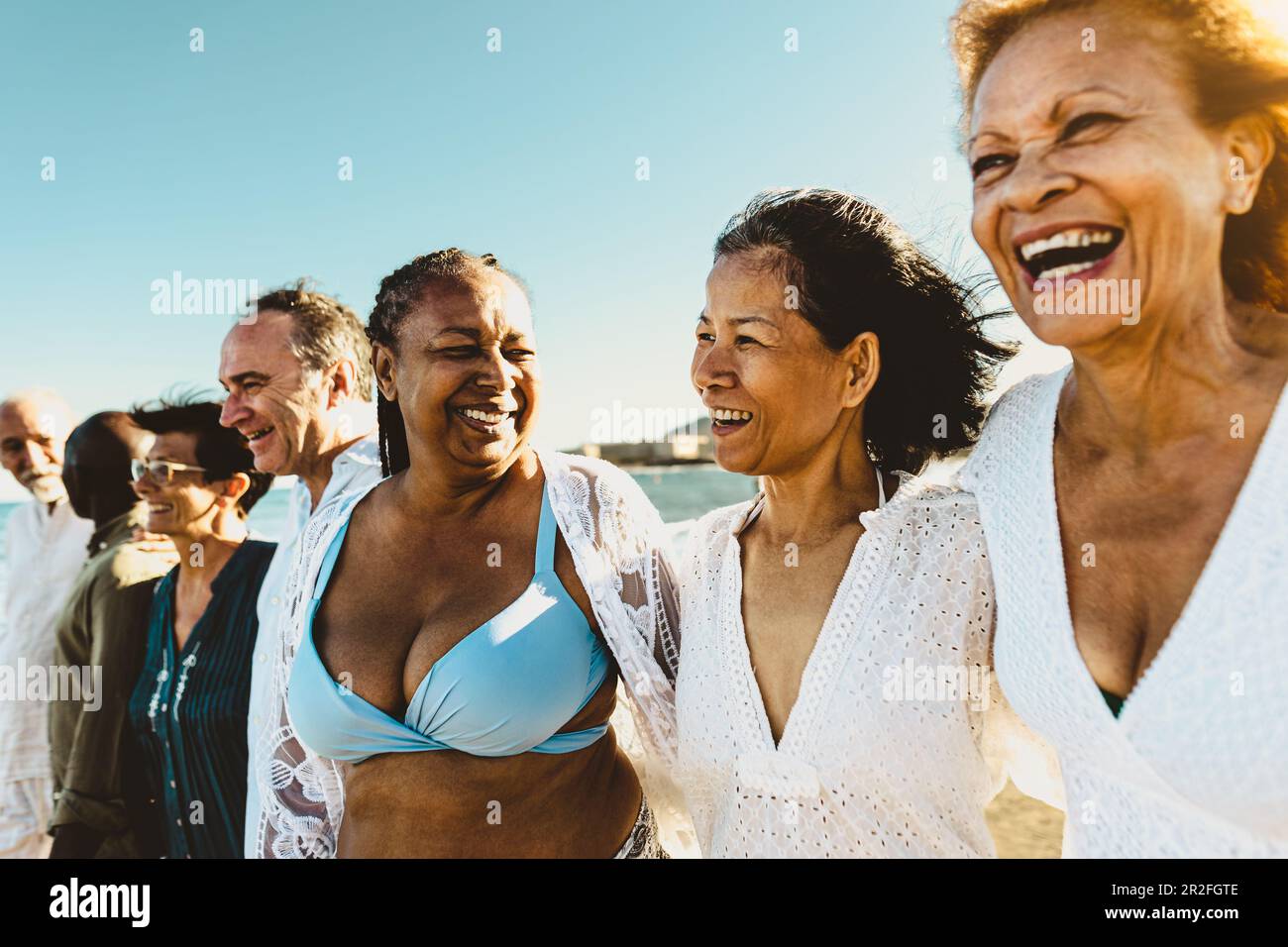 Fröhliche, multirassische Seniorenfreunde, die während der Sommerferien am Strand spazieren gehen - verschiedene ältere Leute genießen den Urlaub Stockfoto Fröhliche, multirassische Seniorenfreunde, die während der Sommerferien am Strand spazieren gehen - verschiedene ältere Leute genießen den Urlaub Stockfoto