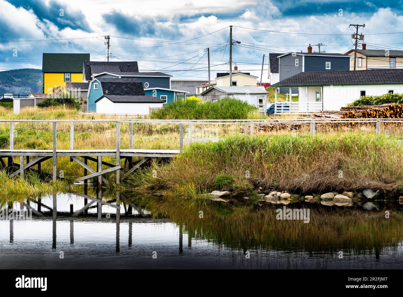 Wasserspiegelung der Boardwalk Bridge am Old Bay Pond mit Blick auf die bunten Neufundland Häuser und Strommasten in Bonavista Canada. Stockfoto