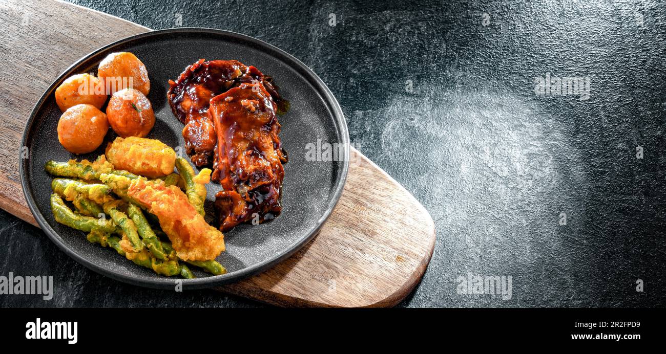 Hähnchenschenkel in Tamarindensauce mit Gemüse Tempura und Kartoffeln Stockfoto