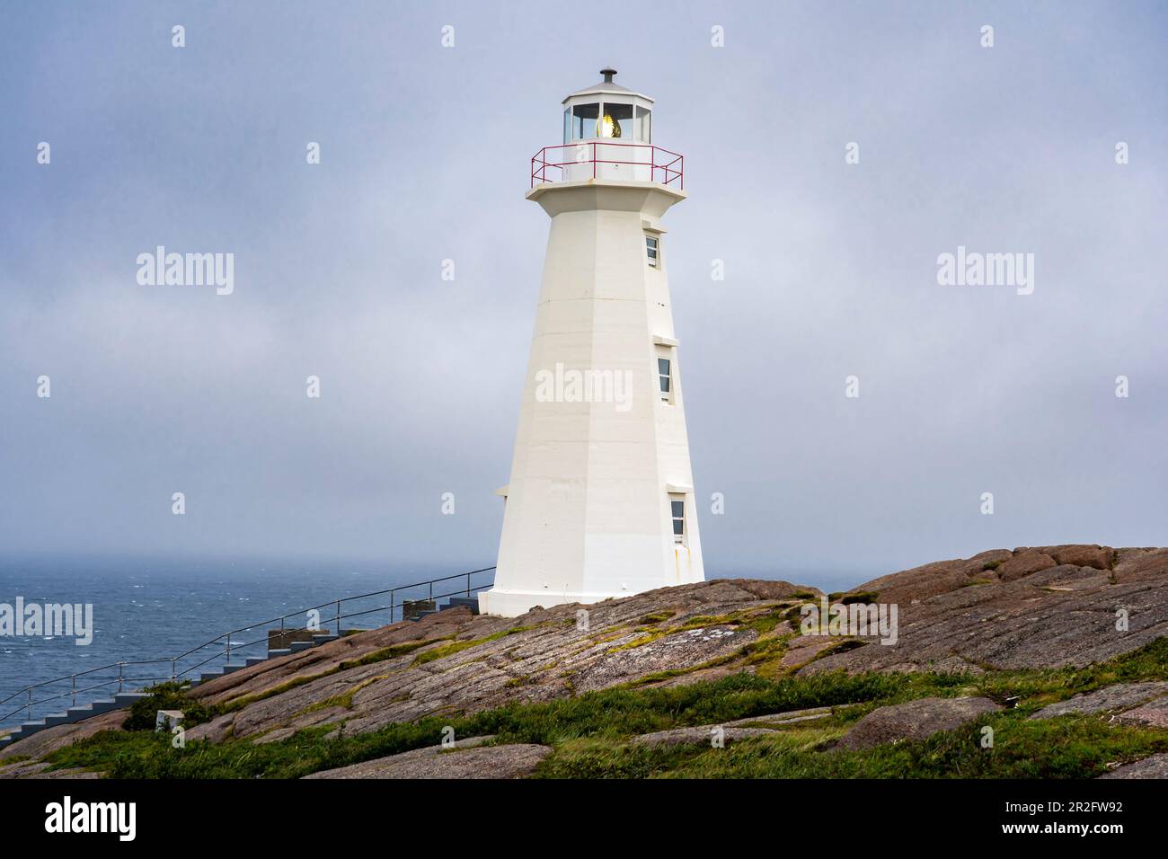 Hoher weißer Leuchtturm an einer felsigen Küste mit Blick auf den Atlantischen Ozean an einem nebligen Tag entlang des East Coast Trail am Cape Spear Newfoundland Can Stockfoto