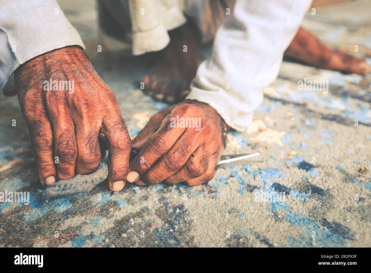 Nahaufnahme von Hand schneiden Teppich mit einer Schere. Teppichreinigung Stockfoto
