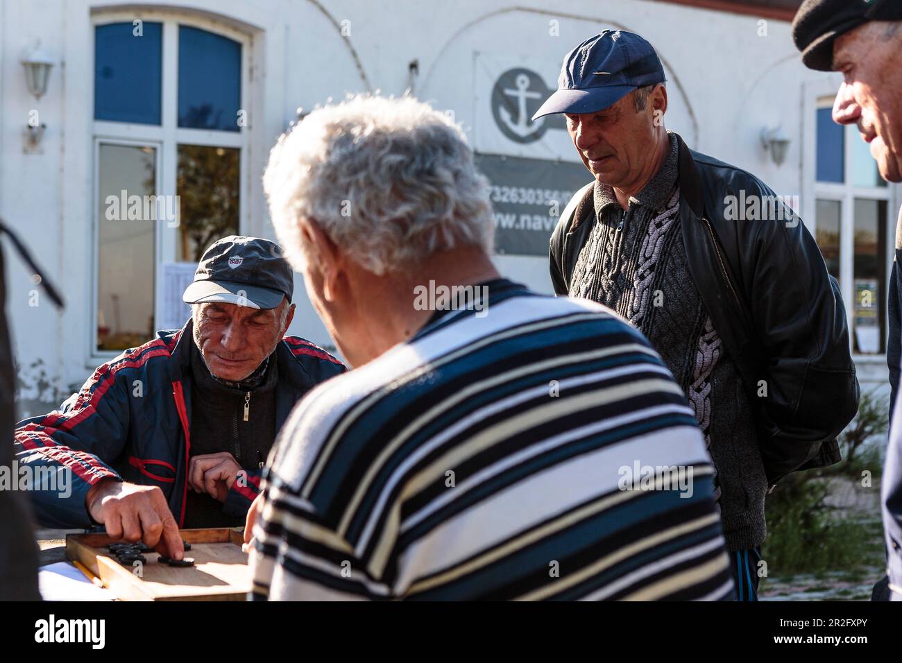 Einige ältere Männer spielen Backgammon in der Innenstadt, Sulina, Tulcea, Rumänien. Stockfoto